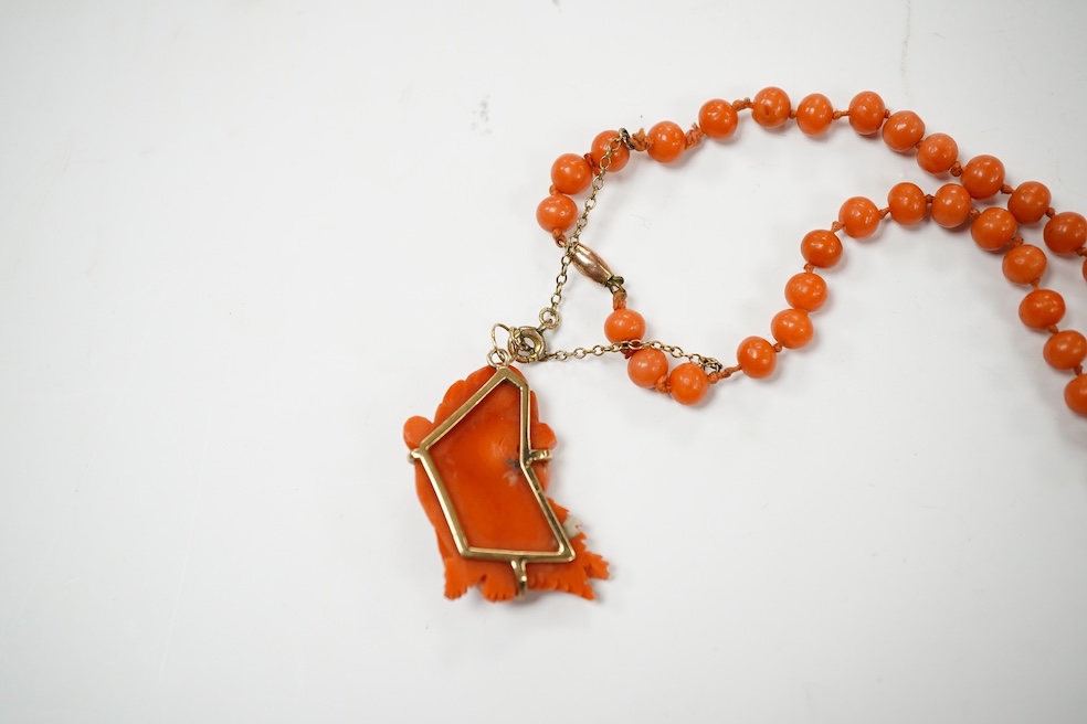 A single strand coral bead necklace, with a coral pendant carved as the face of a gentleman, overall 48cm. Condition - fair